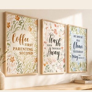 Peut inclure: Trois cadres muraux en bois clair avec des impressions botaniques florales. La première affiche Coffee First Parenting Second, la deuxième Wash Your Troubles Away, et la troisième My House Was Clean Yesterday Sorry You Missed It.