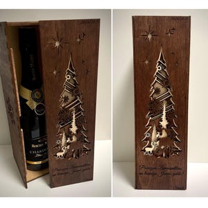 Pode incluir: Uma caixa de madeira com um design de árvore de Natal e veados cortado a laser. A caixa é castanha e tem uma garrafa de vinho dentro. O texto na caixa diz "Przyjacielu, zyczymy Ci wesołych świąt!"