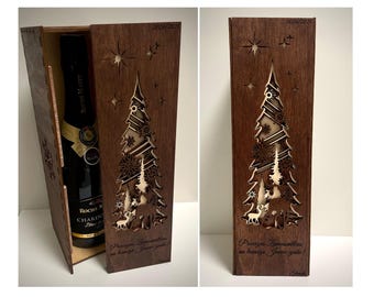 May include: A wooden box with a laser-cut design of a Christmas tree and deer. The box is brown and has a bottle of wine inside. The text on the box reads "Przyjacielu, zyczymy Ci wesołych świąt!"