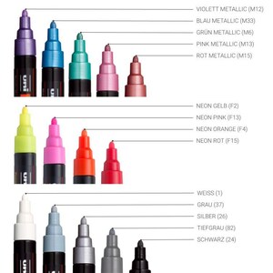 May include: A set of 15 Uni Posca paint markers in various colors, including metallic, neon, and standard colors. The markers are arranged in three rows of five, with the color names and codes listed below each row.