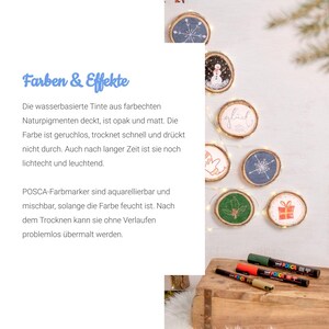 May include: A set of wooden round ornaments with various designs painted on them, including a snowman, a snowflake, a holly leaf, and the word "gl&uuml;ck" (German for "happiness"). The ornaments are strung together with white lights. There are also four Posca paint markers in green, gold, red, and black.
