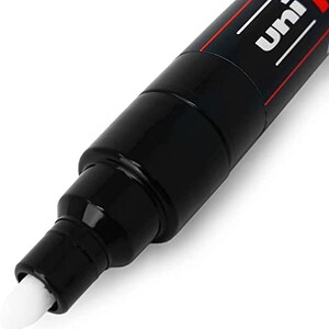 May include: Close-up of a black Uni Posca paint marker with a white tip. The marker has a red stripe and the word "Uni" printed on the side.