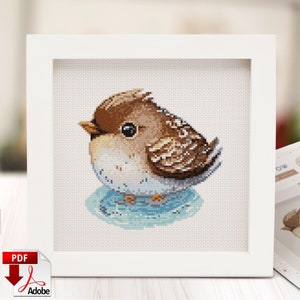 May include: A cross-stitch pattern of a brown and white bird sitting on a blue and white circle. The bird has a round body and a small beak. The pattern is framed in a white frame.