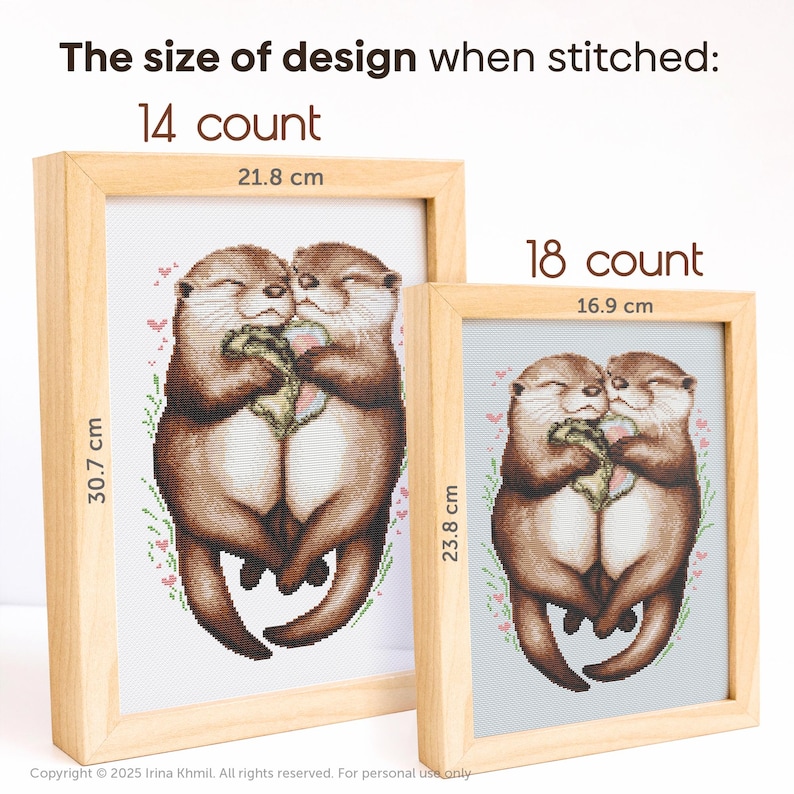 May include: Two otters hugging each other, surrounded by pink flowers. The image shows the finished size of the cross stitch pattern when stitched on 14 count and 18 count Aida fabric. The finished size on 14 count Aida fabric is 21.8 cm by 30.7 cm. The finished size on 18 count Aida fabric is 16.9 cm by 23.8 cm.