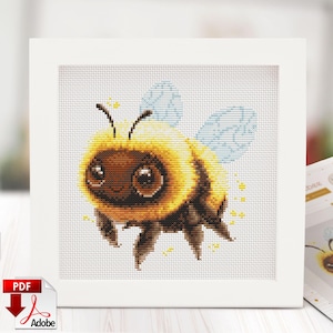 May include: Cross-stitch pattern of a cartoon bee with yellow and brown body, blue wings, and large brown eyes. The bee is surrounded by yellow star-shaped sparkles. The design is framed in a white square.