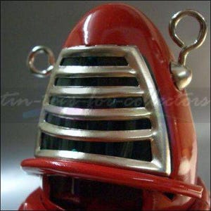 May include: A red and silver robot toy with a grill-like face and two small handles on the top.