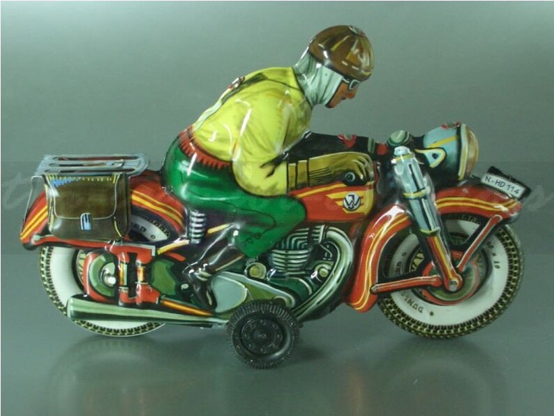 K&ouml;nnte beinhalten: Ein rotes, gr&uuml;nes und gelbes Spielzeugmotorrad mit einem Fahrer, der einen braunen Helm und eine Schutzbrille tr&auml;gt. Das Motorrad hat eine braune Ledertasche und ein Nummernschild mit der Aufschrift "N-HD 114".