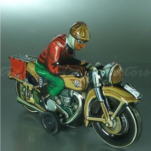 K&ouml;nnte beinhalten: Ein vintage Blechspielzeug-Motorrad mit einem Fahrer, der einen braunen Helm und eine Schutzbrille tr&auml;gt. Das Motorrad ist braun und goldfarben mit schwarzen R&auml;dern und einem Beiwagen. Das Motorrad hat ein Nummernschild mit der Aufschrift "N-JW 14".