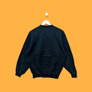 May include: Black sweatshirt with long sleeves and a crew neck.