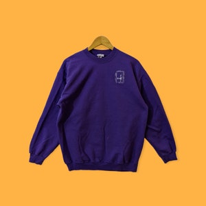 May include: A purple long-sleeved sweatshirt with a white graphic of a deer in a square on the front.