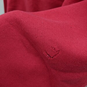 May include: A close-up of a red fabric with a small hole in the center.