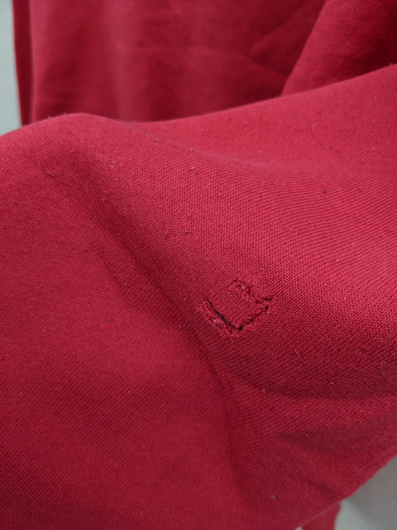 May include: A close-up of a red fabric with a small hole in the center.