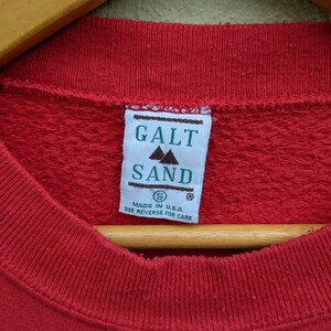 May include: Red sweatshirt with a green tag that reads "Galt Sand" and "Made in U.S.A. See reverse for care".