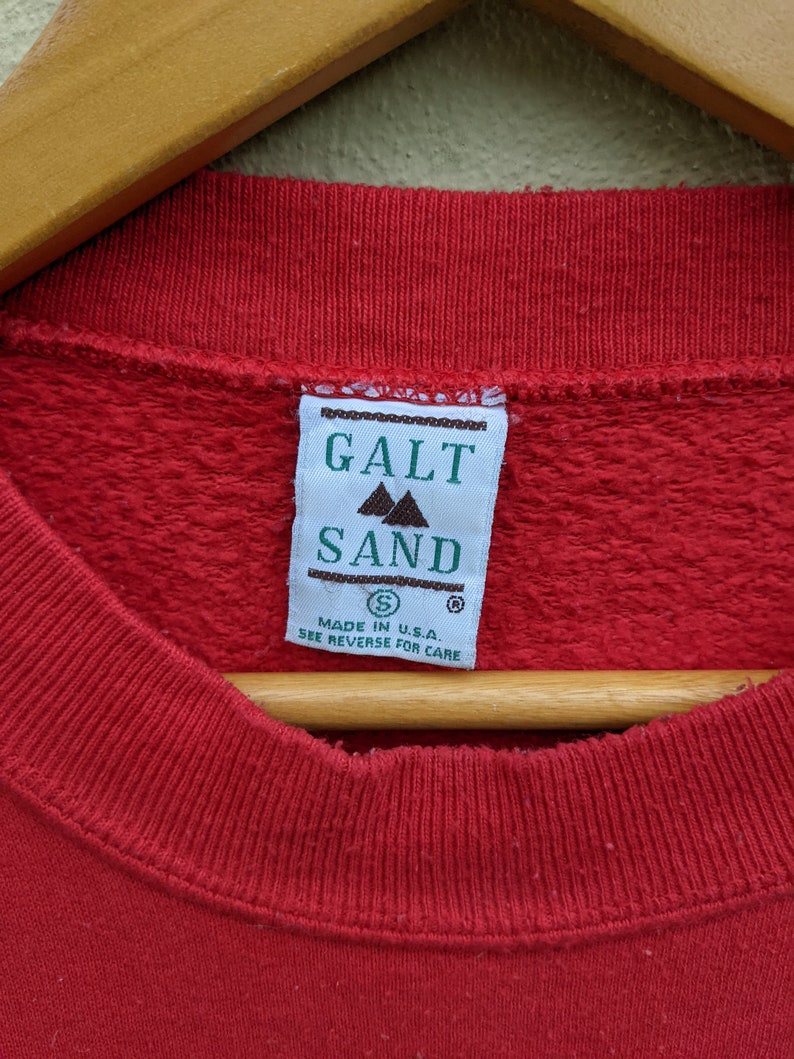 May include: Red sweatshirt with a green tag that reads "Galt Sand" and "Made in U.S.A. See reverse for care".
