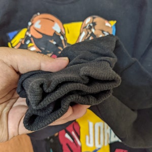 May include: Black long-sleeve shirt with a graphic print of two basketball players and the text "Air Jordan". The shirt has a ribbed cuff.