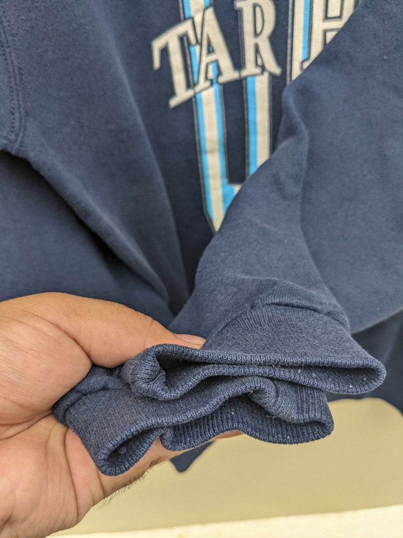 May include: Close-up of the navy blue cuff of a sweatshirt. The cuff is folded over three times, showing the soft, knitted fabric.