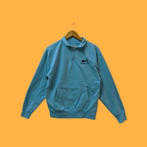 Könnte beinhalten: Ein hellblauer Quarter-Zip-Sweatshirt mit einem schwarzen gestickten Logo einer Karte von Cape Cod und dem Text "CAPE COD".