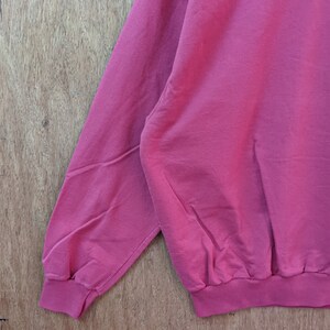 May include: A close-up of the sleeve and bottom hem of a red sweatshirt. The sweatshirt has a ribbed cuff and hem.