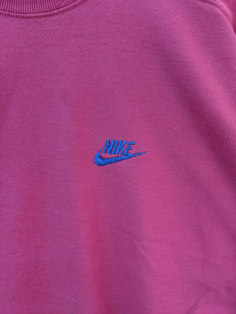 May include: A maroon sweatshirt with a blue embroidered Nike logo.