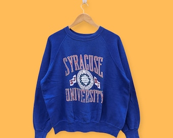 May include: A blue sweatshirt with the words "Syracuse University" in red and white lettering. The sweatshirt has a vintage look and feel.