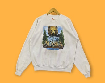 May include: White sweatshirt with a brown bear and the text "Alaska 7-Day Cruises & Tours" printed on the front.