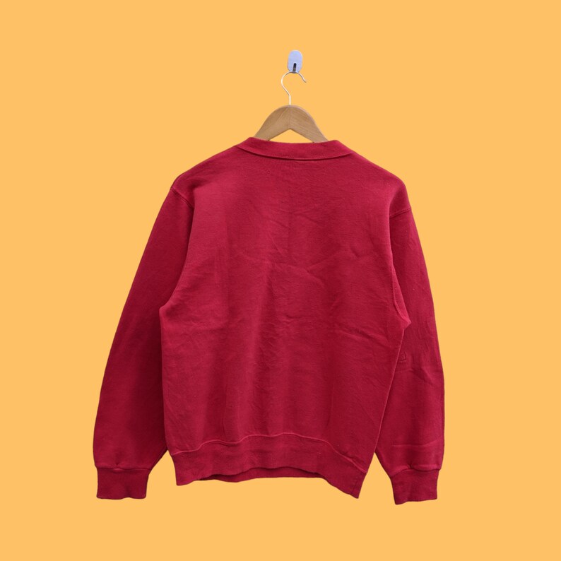 May include: A red long-sleeved sweatshirt with a crew neck.