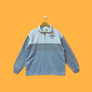 May include: A gray, blue, and white striped quarter-zip sweatshirt with the text "Sunriver Oregon" embroidered on the chest.