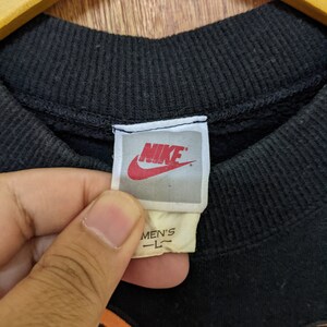 May include: Black sweatshirt with a Nike logo and the text "MEN'S L" on the tag. The sweatshirt features a cartoon graphic of two people.