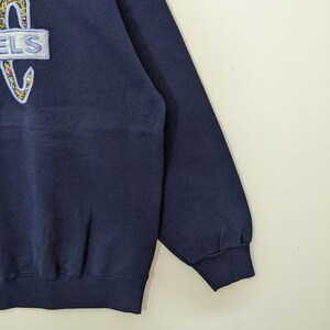 Peut inclure: Un sweat-shirt bleu marine avec un logo brod&eacute; color&eacute; qui dit "ELS" sur le devant. Le sweat-shirt a des manches longues et un ourlet c&ocirc;tel&eacute;.