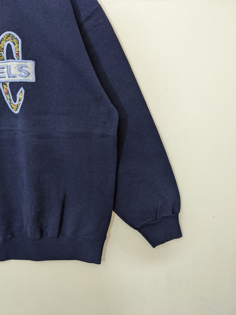 Peut inclure: Un sweat-shirt bleu marine avec un logo brod&eacute; color&eacute; qui dit "ELS" sur le devant. Le sweat-shirt a des manches longues et un ourlet c&ocirc;tel&eacute;.