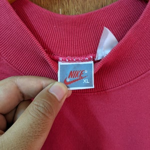 May include: Red Nike sweatshirt with a white tag that says "NIKE" and "XL" in black.
