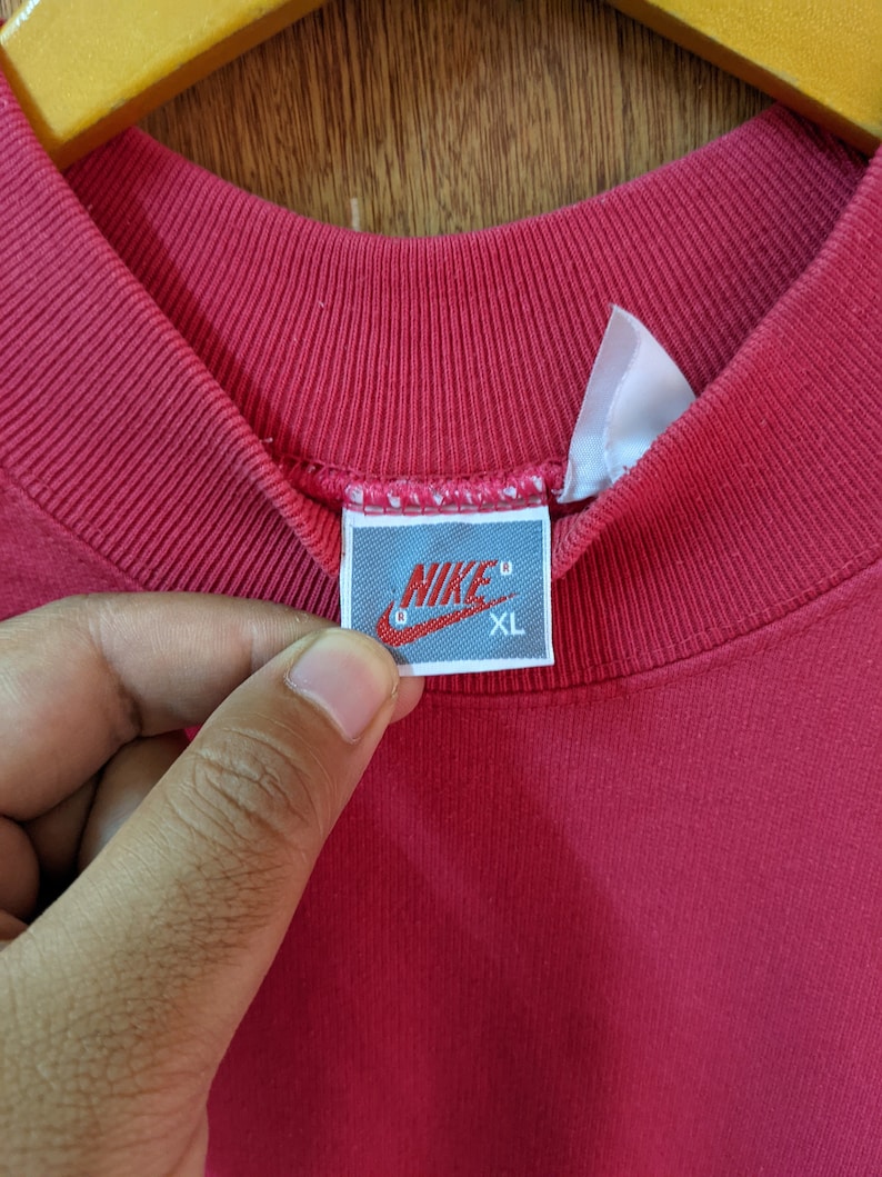 May include: Red Nike sweatshirt with a white tag that says "NIKE" and "XL" in black.