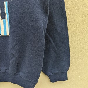 May include: A dark blue sweatshirt with a graphic of a bottle with blue and white stripes and the text "S" and "LS" on the front.