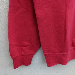 May include: A red sweatshirt with long sleeves and a ribbed cuff. The sweatshirt is made of a soft, comfortable fabric.