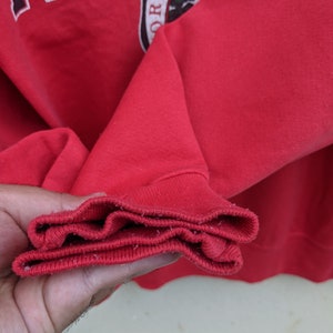 May include: Close-up of the red ribbed cuff of a red sweatshirt. The cuff is folded over three times.