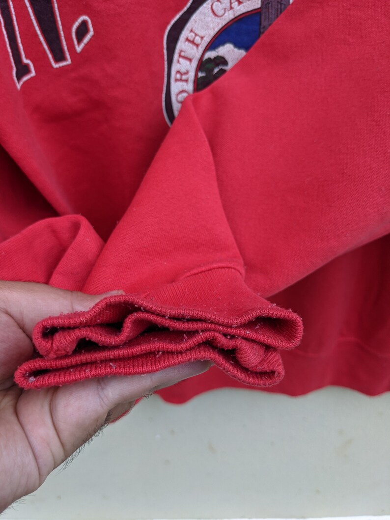 May include: Close-up of the red ribbed cuff of a red sweatshirt. The cuff is folded over three times.