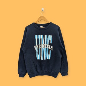 May include: A navy blue sweatshirt with a white and blue striped graphic of the letters "UNC" with the words "Tar Heels" in white lettering.