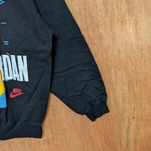 May include: Black sweatshirt with a colorful graphic print of the word "AIR JORDAN" and the Nike logo.