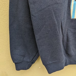 May include: A dark blue sweatshirt with a ribbed cuff. The sweatshirt is made of a soft, comfortable fabric.