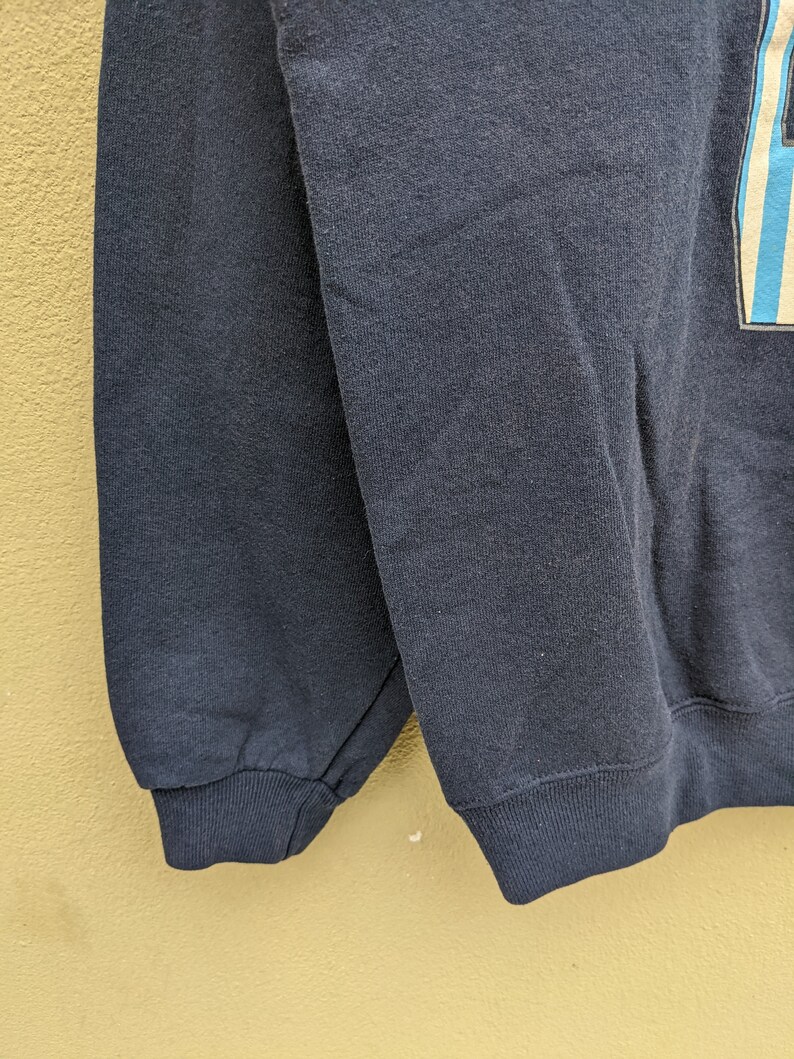 May include: A dark blue sweatshirt with a ribbed cuff. The sweatshirt is made of a soft, comfortable fabric.