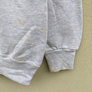 May include: A gray sweatshirt with a ribbed cuff. The sweatshirt has a few light brown stains.