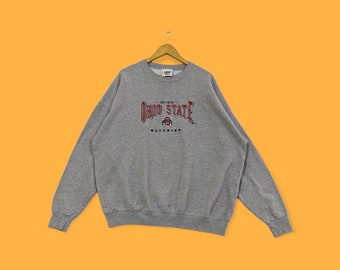 May include: Gray sweatshirt with a red and black Ohio State Buckeyes logo. The logo includes the text "EST. 1870 OHIO STATE BUCK EYES."