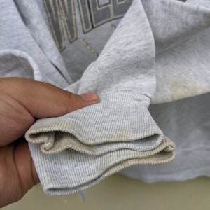 May include: Close-up of the gray ribbed cuff of a sweatshirt. The cuff is folded over twice, showing the inside of the fabric.
