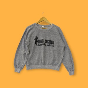May include: A gray sweatshirt with a black graphic of a runner and the text "Bob Schul Racing Team".