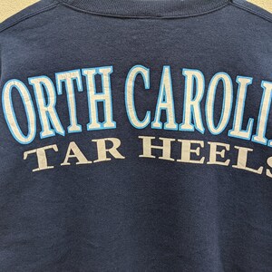 May include: A navy blue sweatshirt with the text "North Carolina Tar Heels" in white and blue lettering.