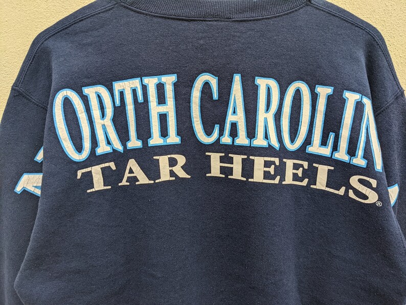May include: A navy blue sweatshirt with the text "North Carolina Tar Heels" in white and blue lettering.