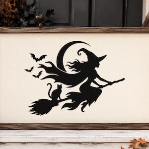May include: A rectangular wooden sign with a cream-colored background featuring a black silhouette of a witch flying on a broomstick with a cat, a crescent moon, and three bats. The sign is enclosed in a dark brown stained wooden frame.
