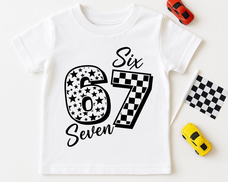 Pu&ograve; includere: T-shirt bianca con i numeri "6" e "7" in nero. Il numero "6" &egrave; riempito di stelle, e il "7" ha un motivo a scacchi. Le parole "Six" e "Seven" sono scritte in corsivo. Sono presenti anche piccole macchinine giocattolo e una bandiera a scacchi.