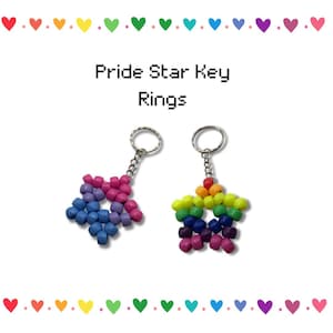 May include: Two star-shaped keychains made of colorful beads. One keychain features a gradient of blue, purple, and pink beads. The other has a rainbow of colors. The text "Pride Star Key Rings" is above the keychains.