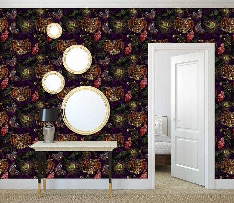 May include: A hallway with a dark purple wallpaper featuring a repeating pattern of owls, hearts, keys, and ferns. The wallpaper has a vintage, gothic aesthetic. There is a console table with a lamp and four gold-framed mirrors on the wall.